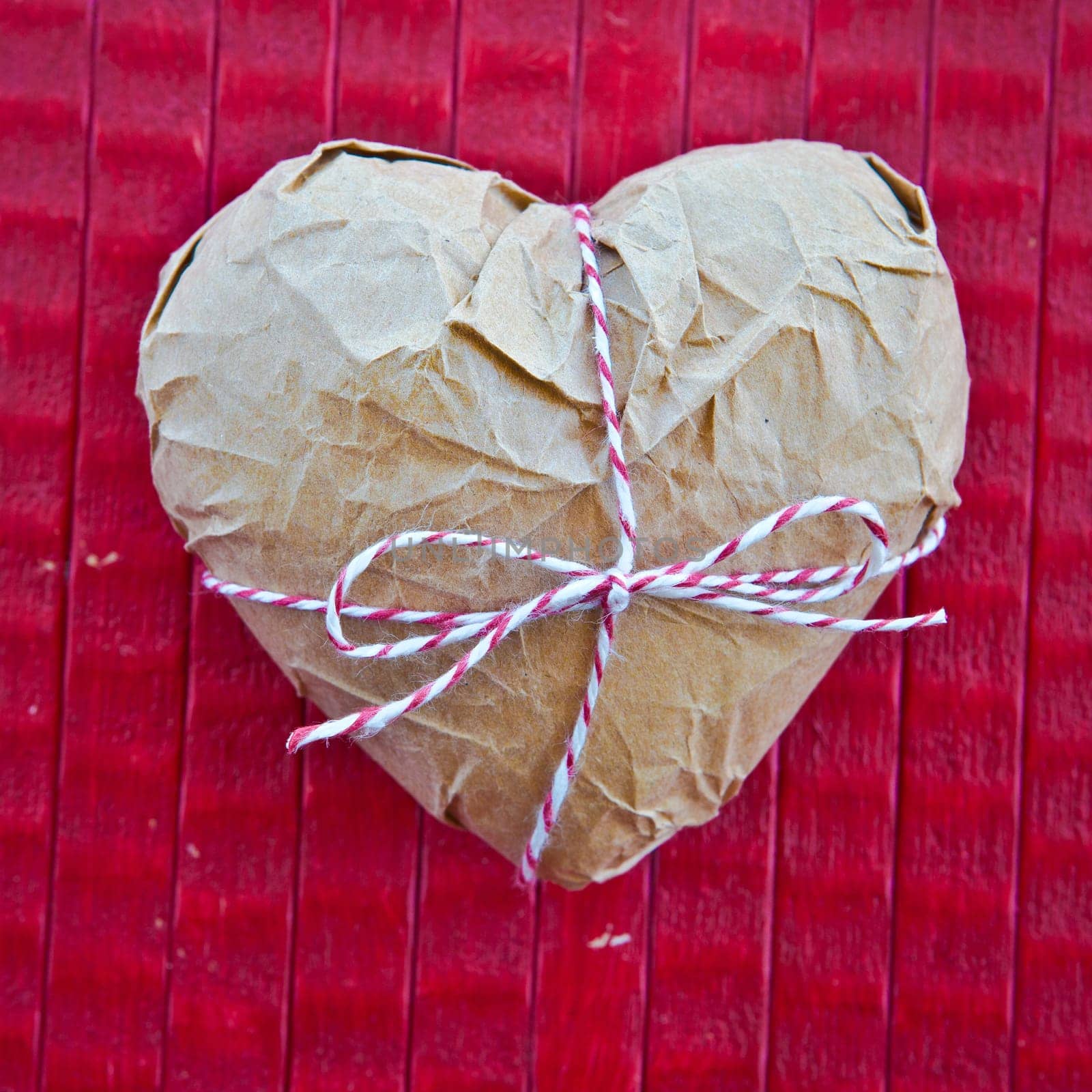 Heart in parcel paper on red background