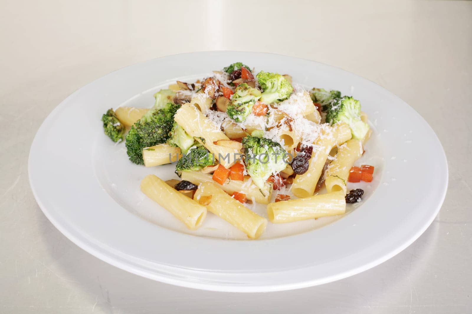 Rigatoni with vegetables served on a white plate.