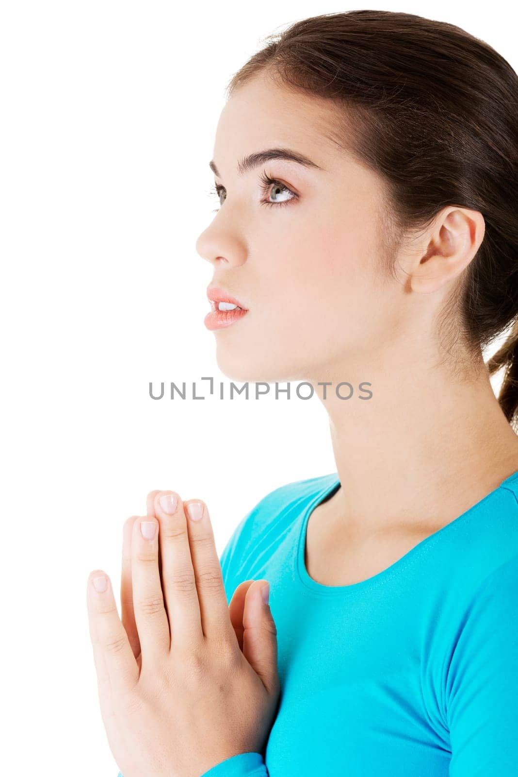 young pretty caucasian girl praying over white background.