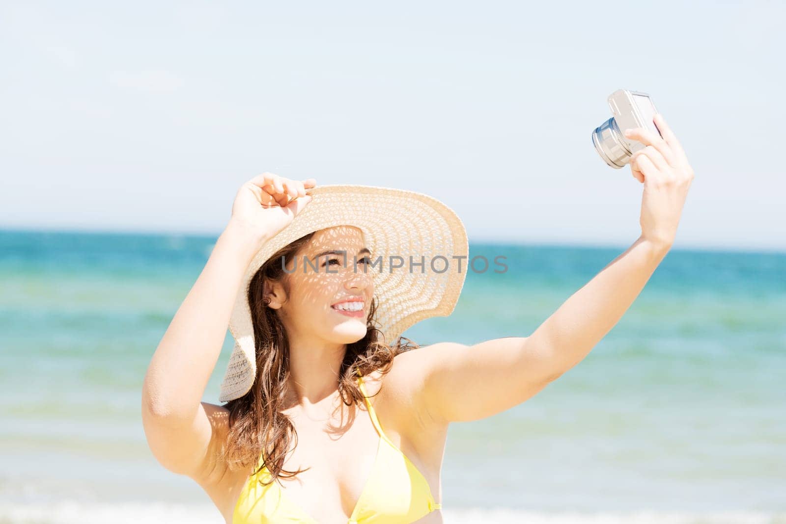Attractive cheerful summer woman talking pictures with digital camera.