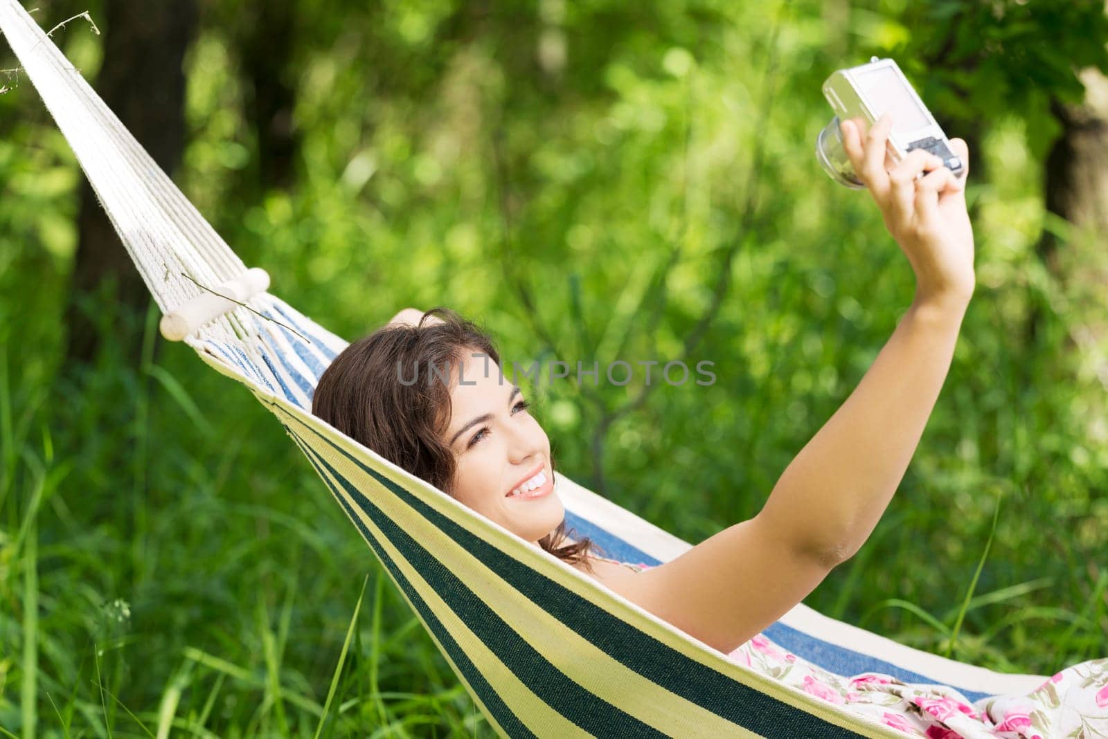 young woman lying in a hammock in the garden doing snapshot.