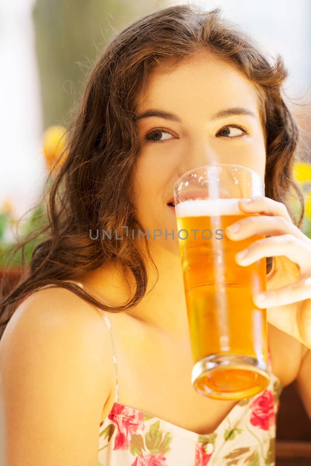 Attractive young woman drinking beer on sidewalk cafe.