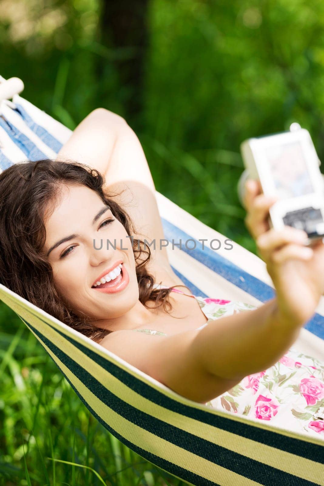 young woman lying in a hammock in the garden doing snapshot.