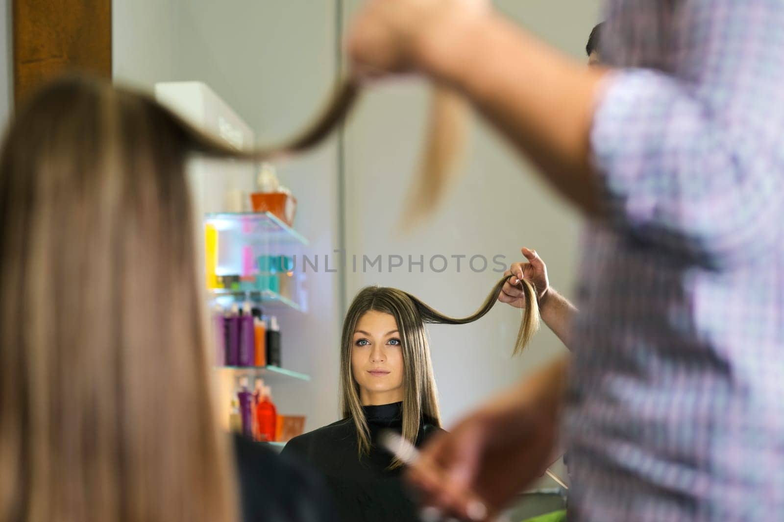 woman looking at mirron and cutting hair in hairdresser shop