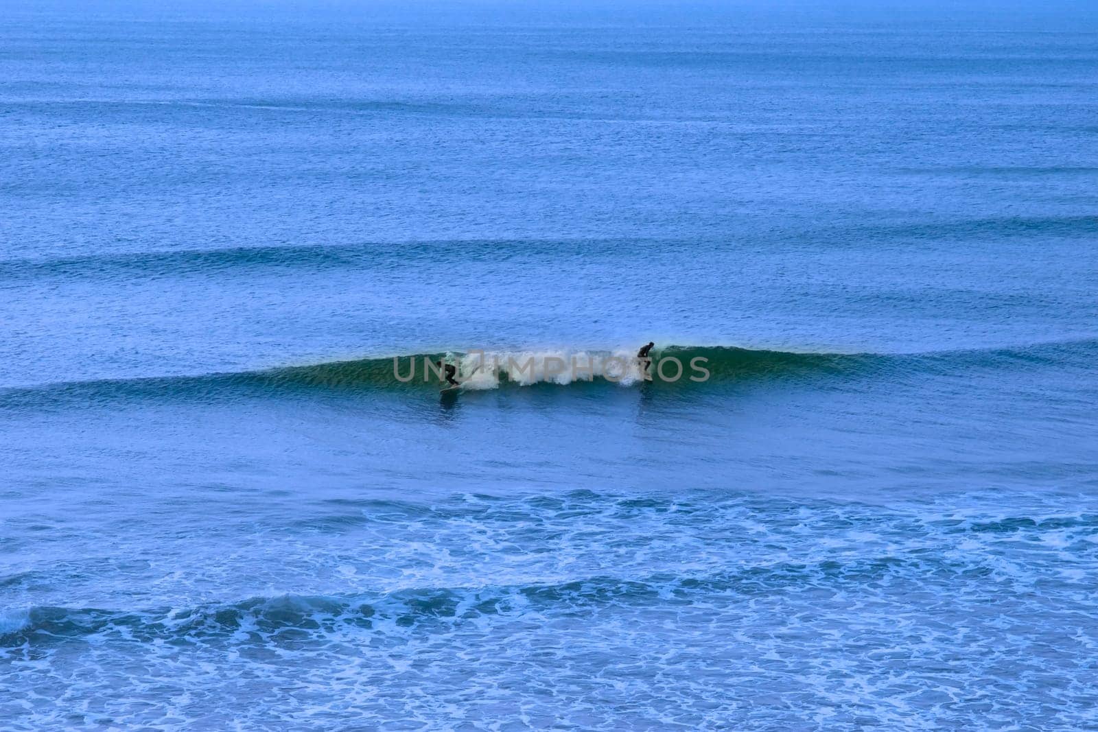 beautiful clean atlantic ocean with two surfers catching the waves on Irelands coast