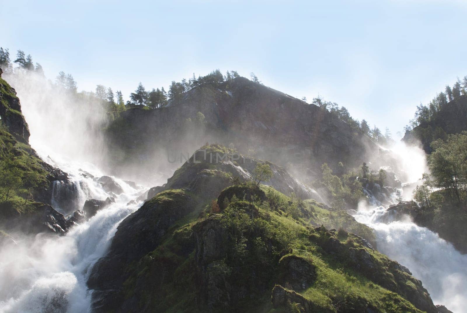 two waterfalls in the sun with trees around it