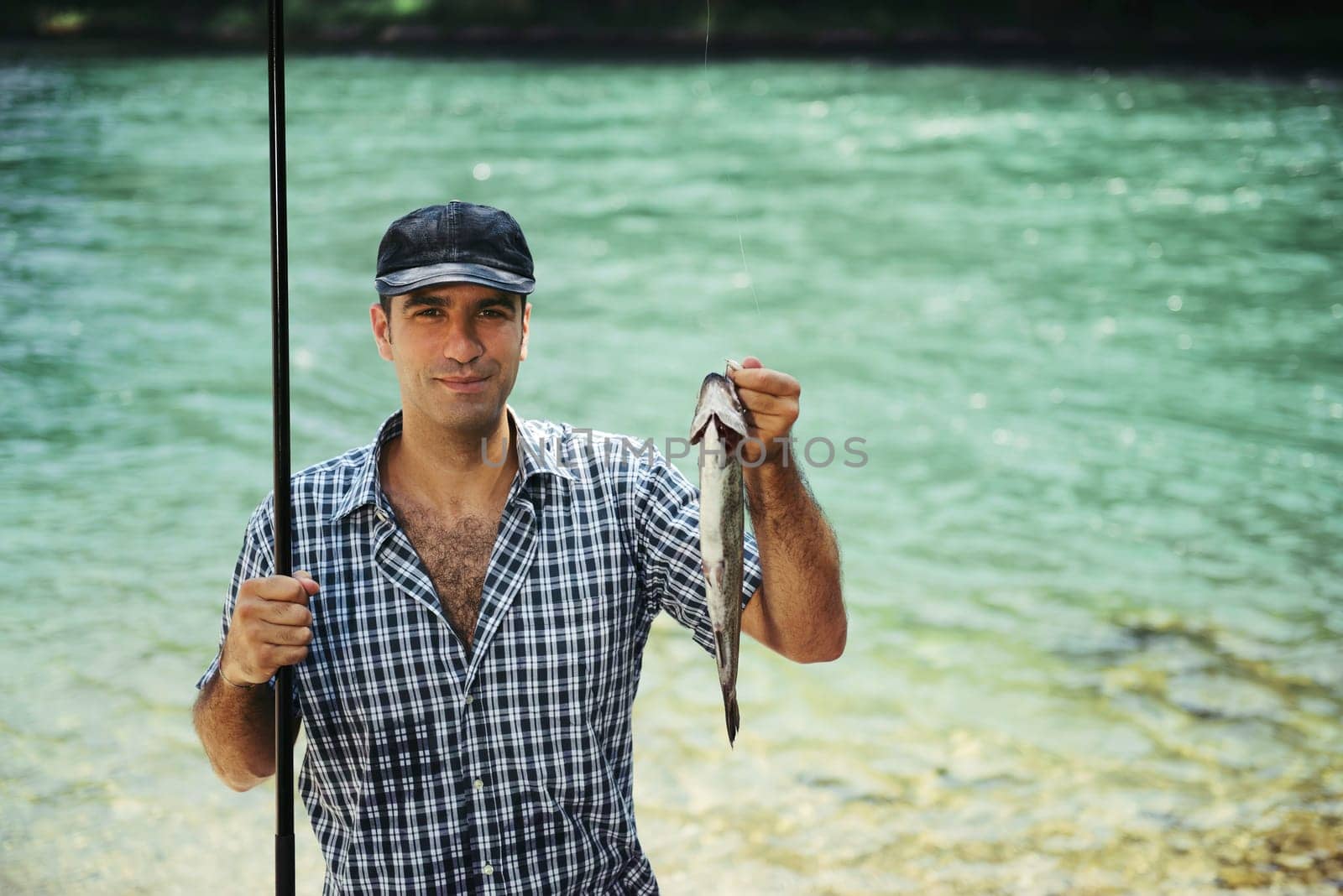mid adult fisherman on holidays on river, relaxing and fishing trout. Copy space