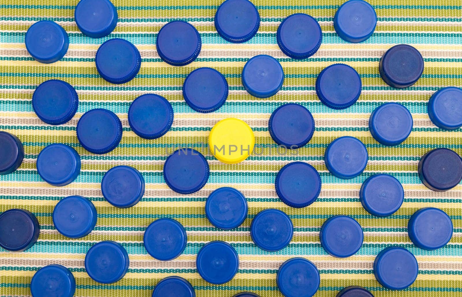 Many blue plastic lids and in the middle one yellow lid.