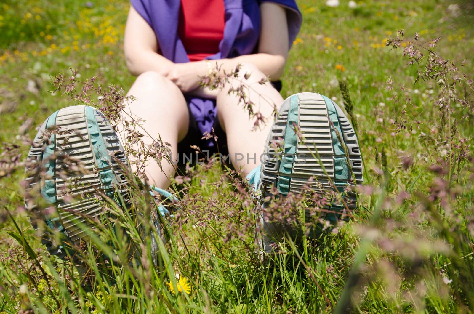 Woman sits in a green meadow in the mountains and takes a break