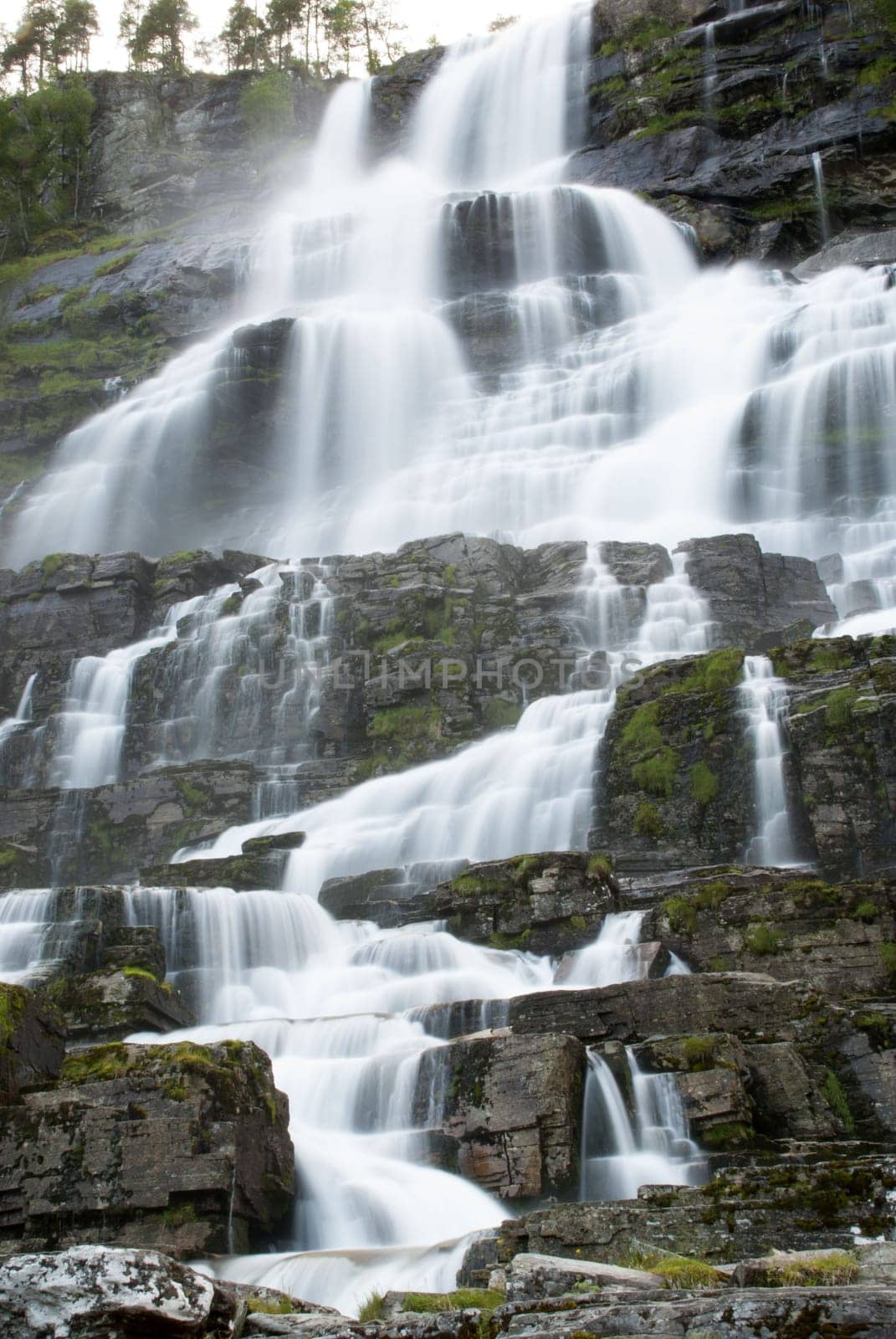 a waterfall in norway, water running down stones in cascades