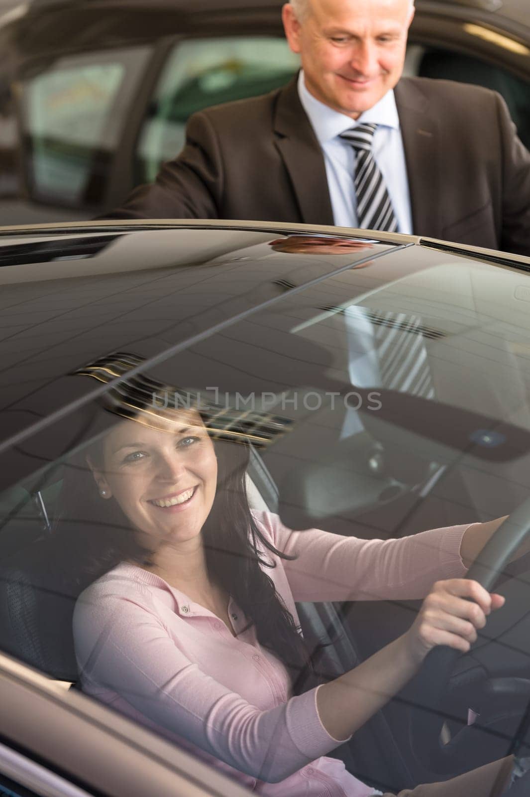 Young Caucasian woman testing car in showroom