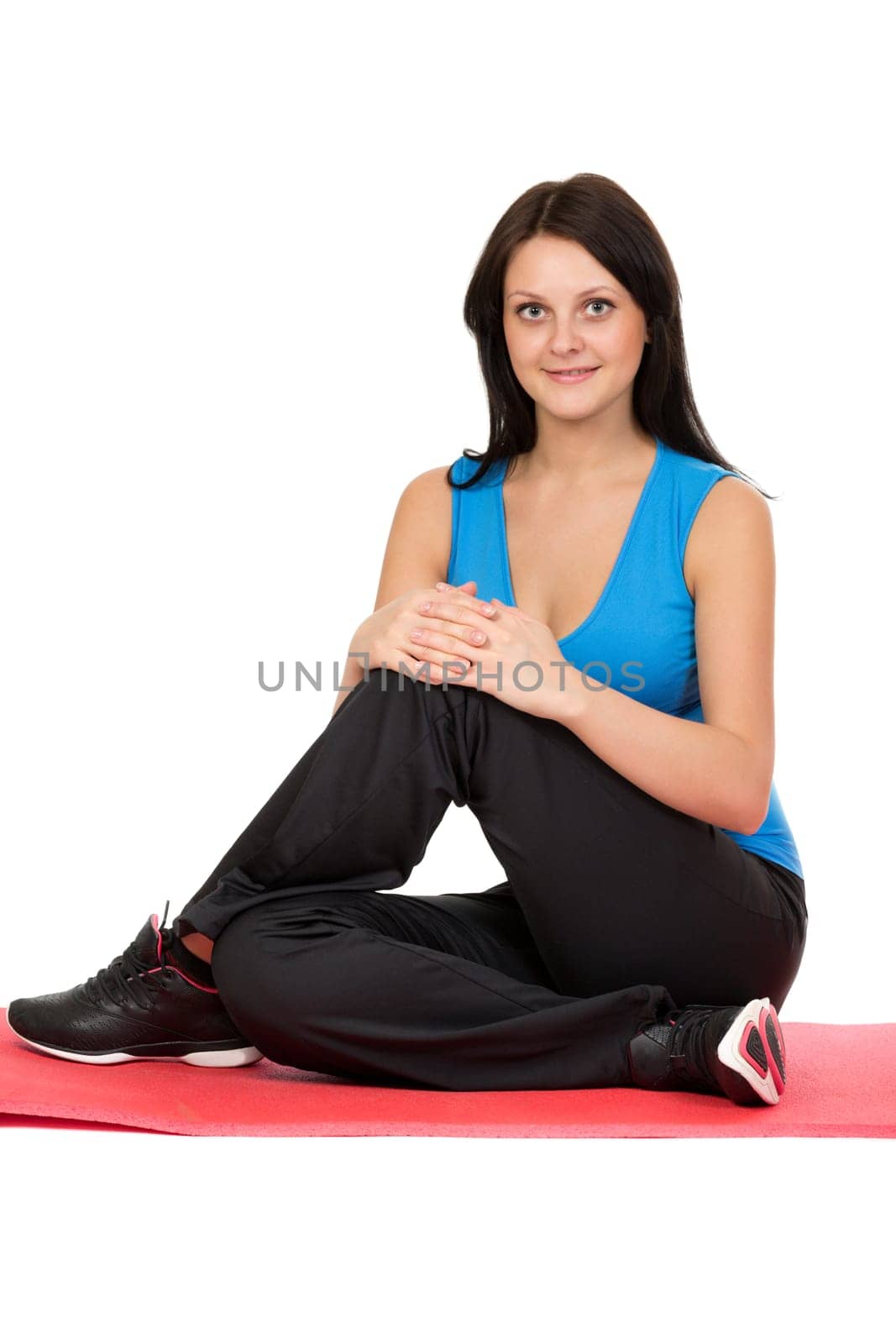 Cute brunette in sportswear sitting on a yoga mat