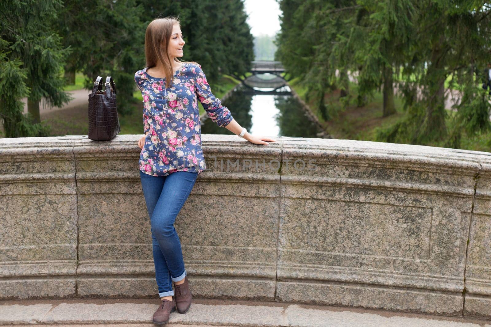 Beautiful young girl on the old stone bridge in the coniferous forest