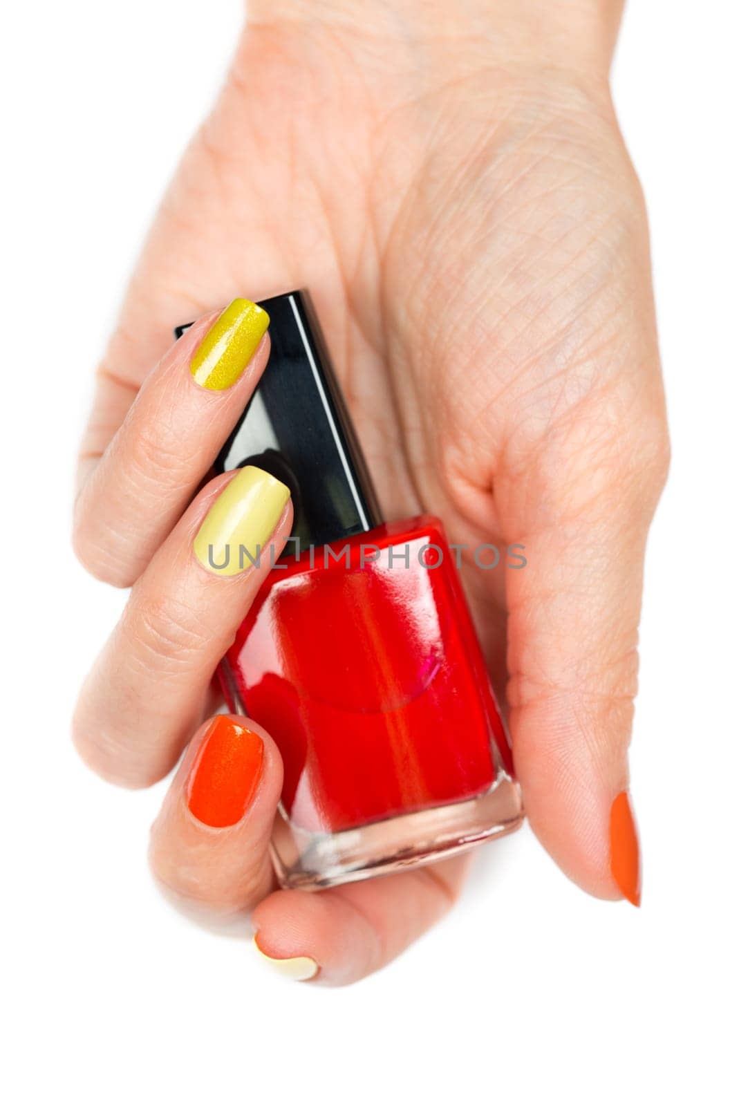 A bottle of red nail polish in a female hand. Isolated on white background