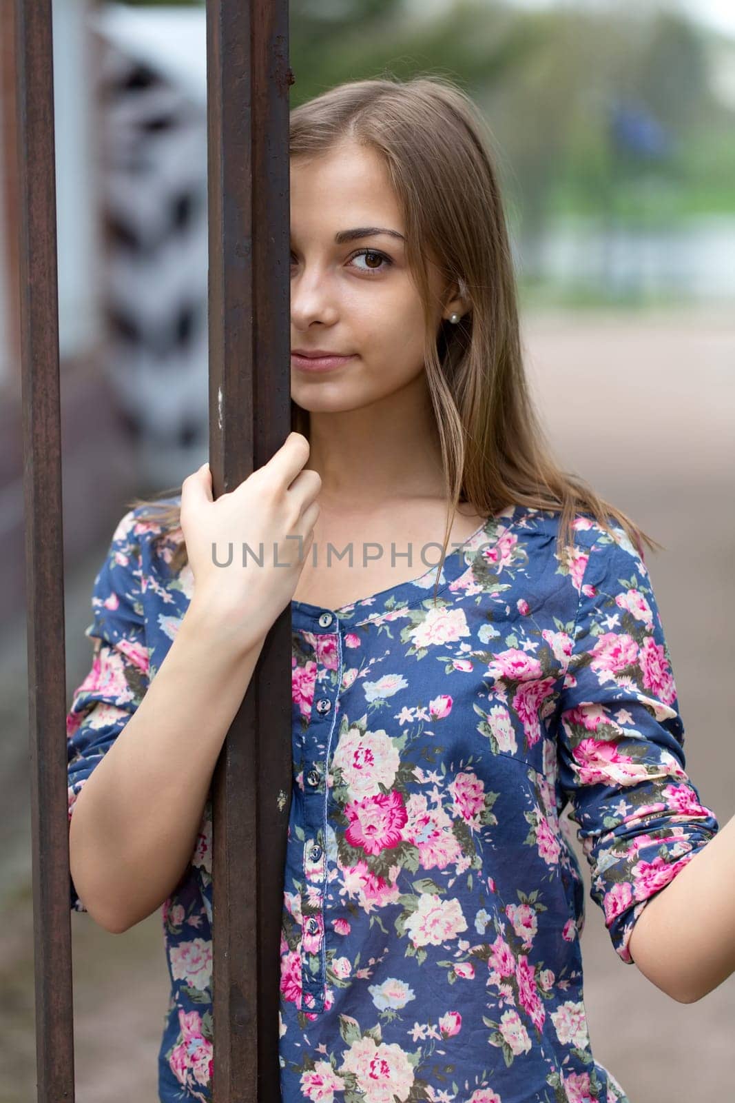 Portrait of a brunette against a metal fence forged