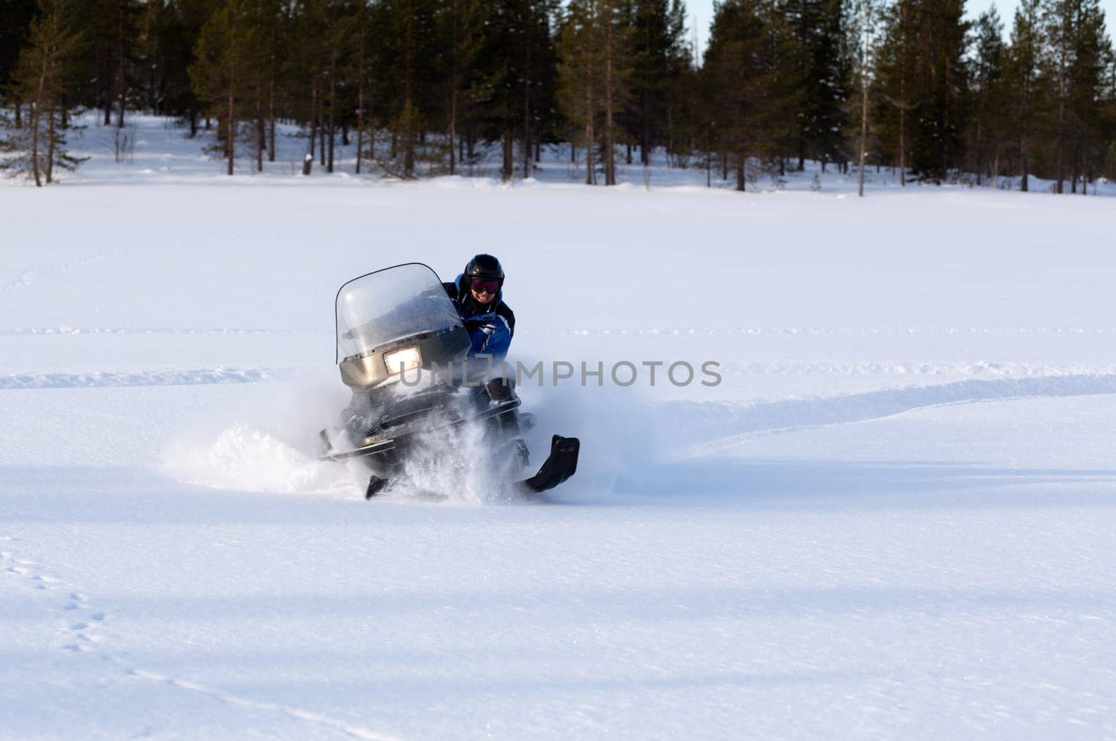 man riding a snowmobile on a background of forest