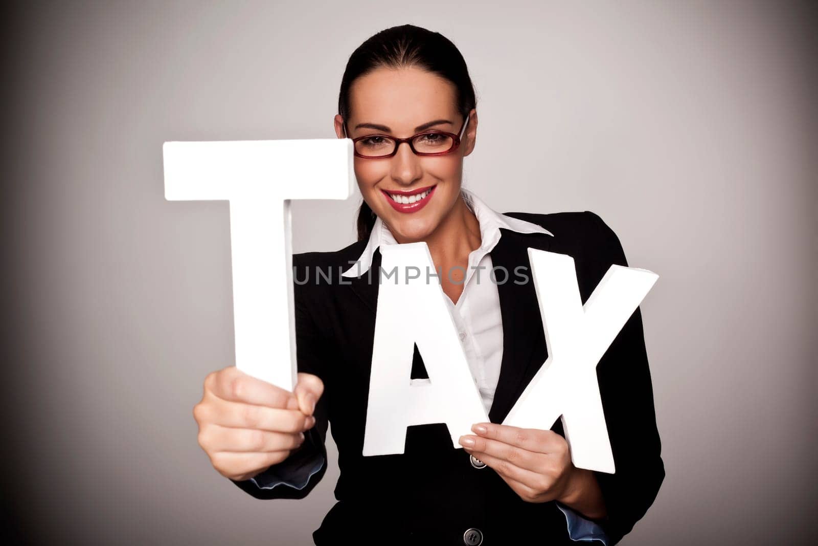 A businesswoman holding letters to spell out tax as a pay your tax concept.