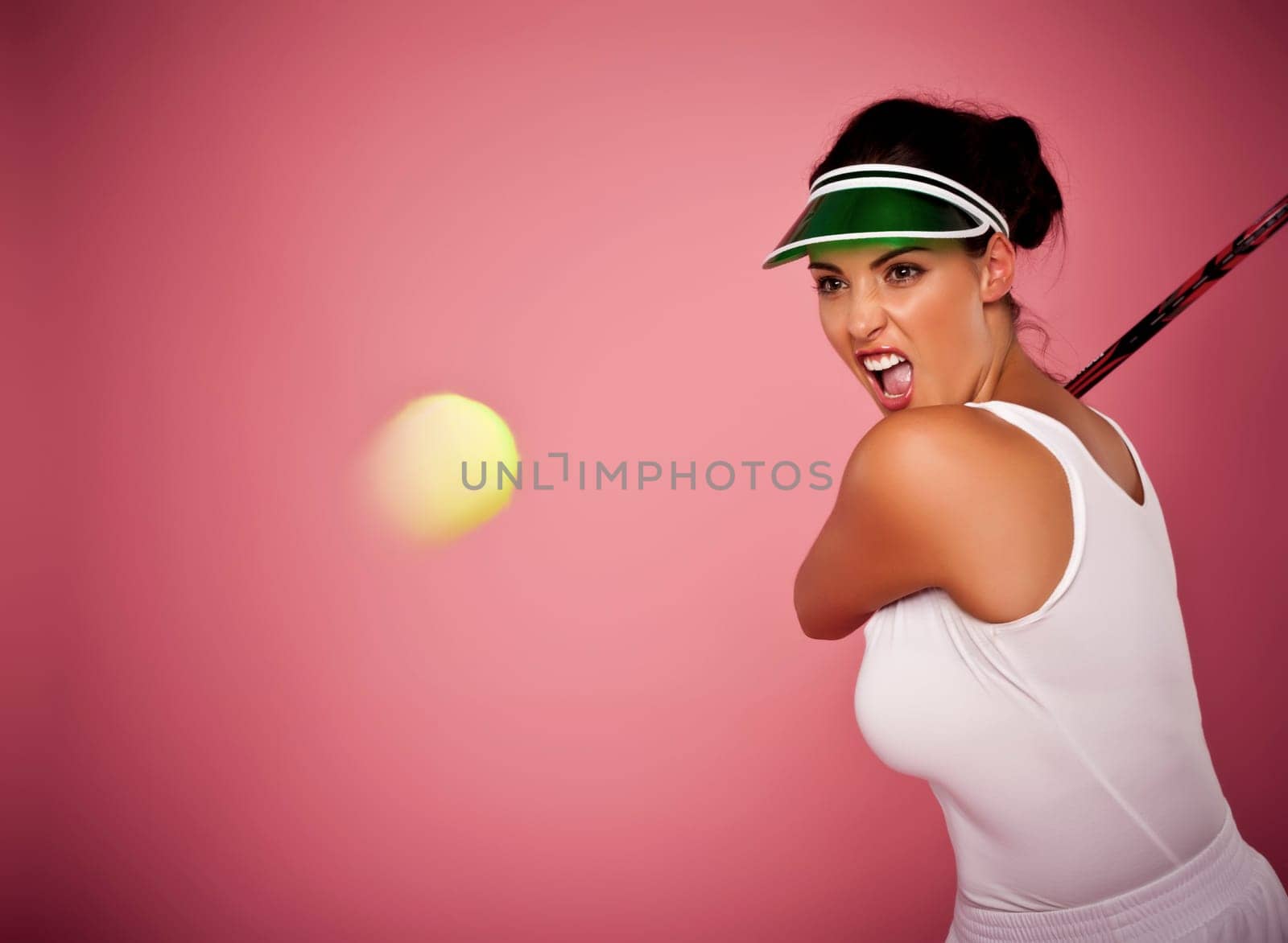 A beautiful woman enjoying the great game of tennis on a pink background.