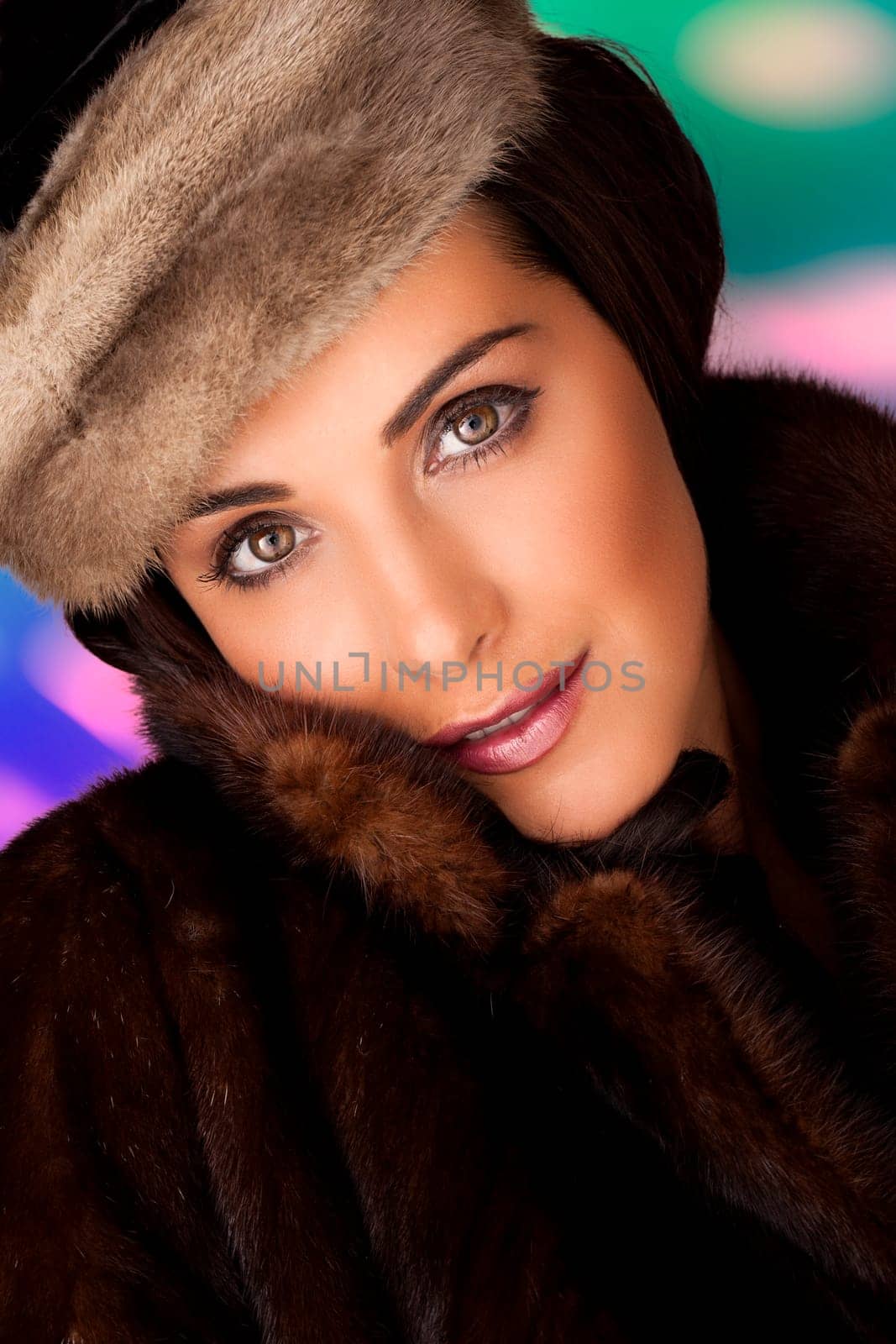 A beautiful woman wearing a warm fur coat on a colorful background.