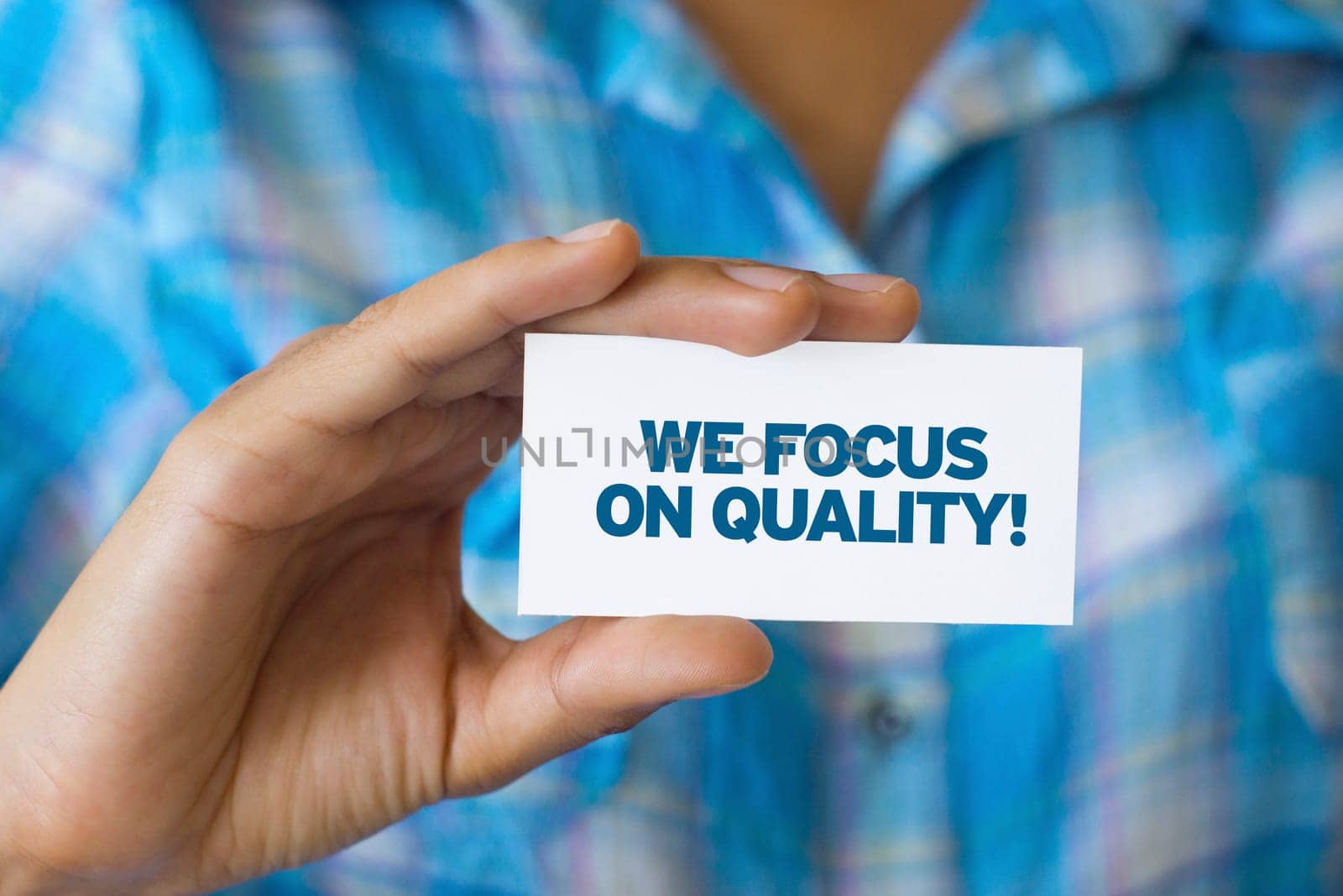 A person holding a white card with the words We focus on quality