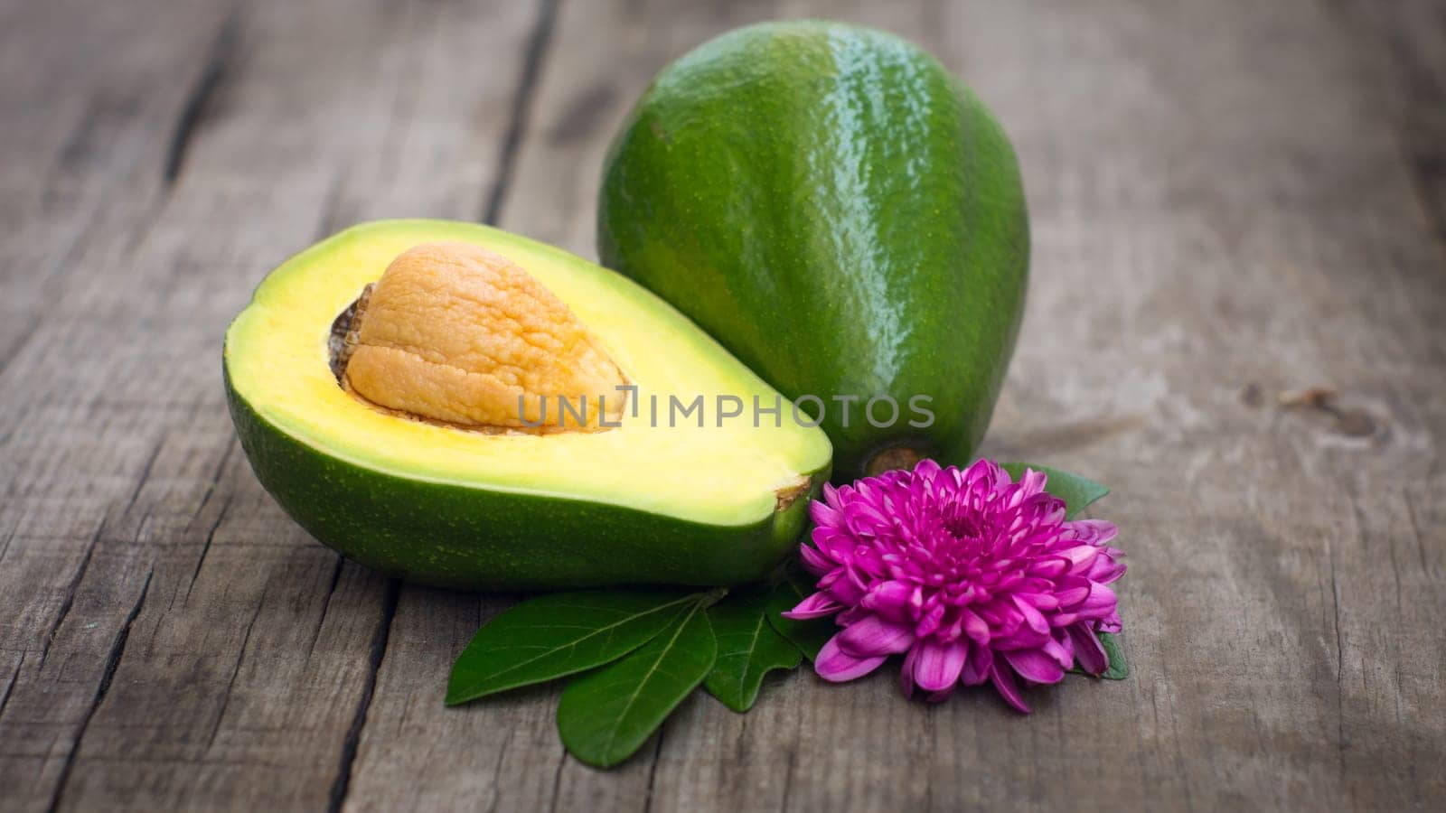Avacado fruit with green leaves and flower on wood background