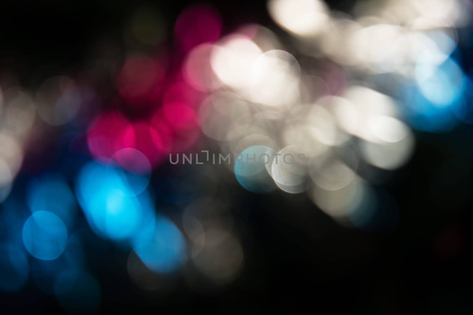 Holiday abstraction. Multi-colored bright glare on dark background