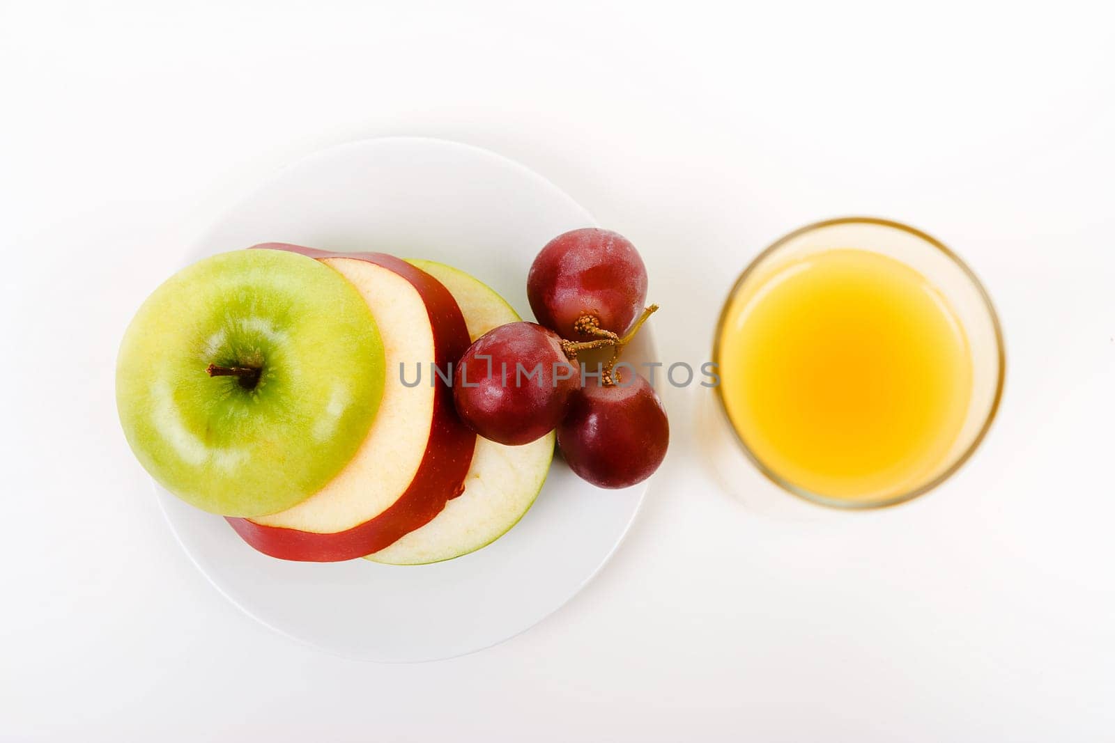 Apple, grapes on a plate and a glass of orange juice. top view