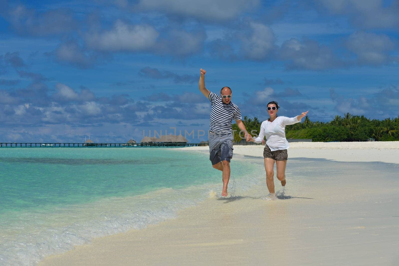 happy young couple have fun and relax at summer vacation on background maldives travel location and beautiful white sand beach