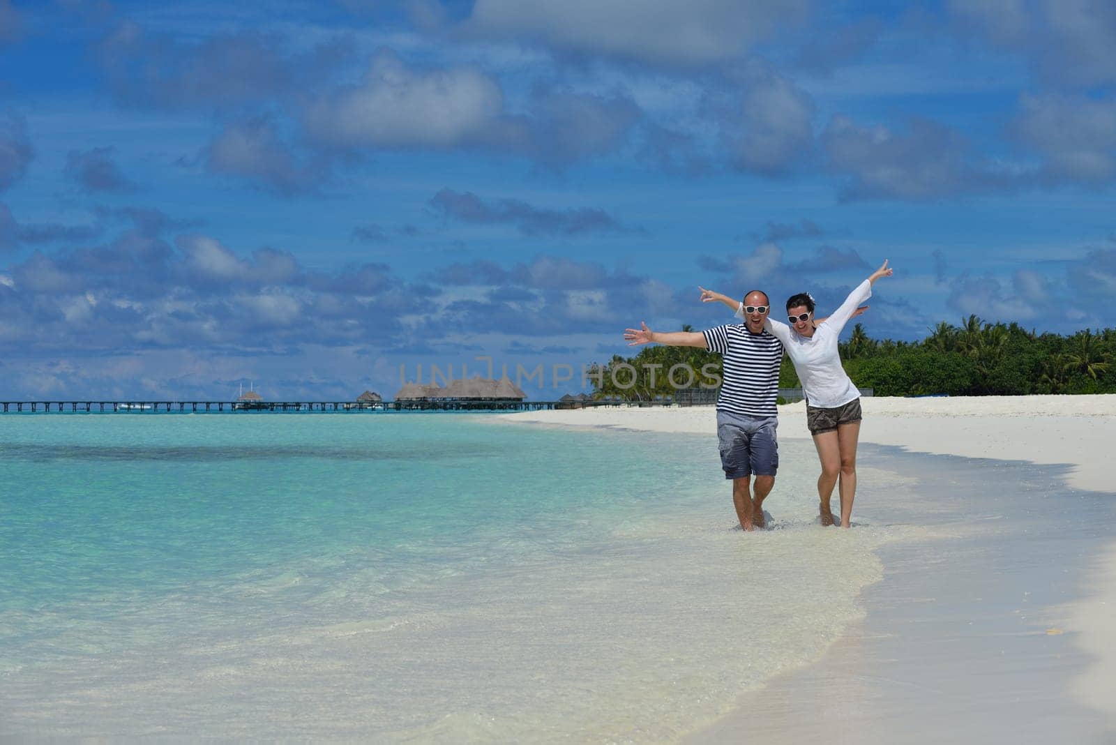 happy young couple have fun and relax at summer vacation on background maldives travel location and beautiful white sand beach