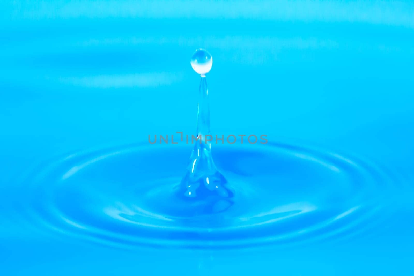 Water droplets drip into blue water