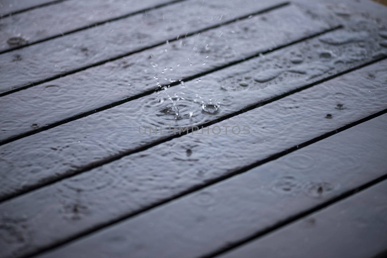 Splashing raindrops on wooden deck close-up