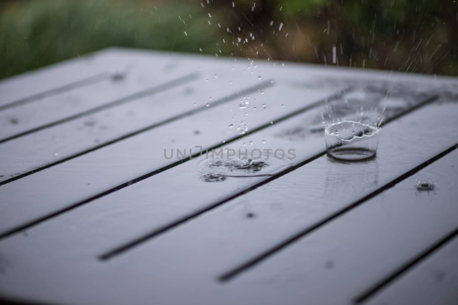Splashing rain water droplets on wooden deck close-up