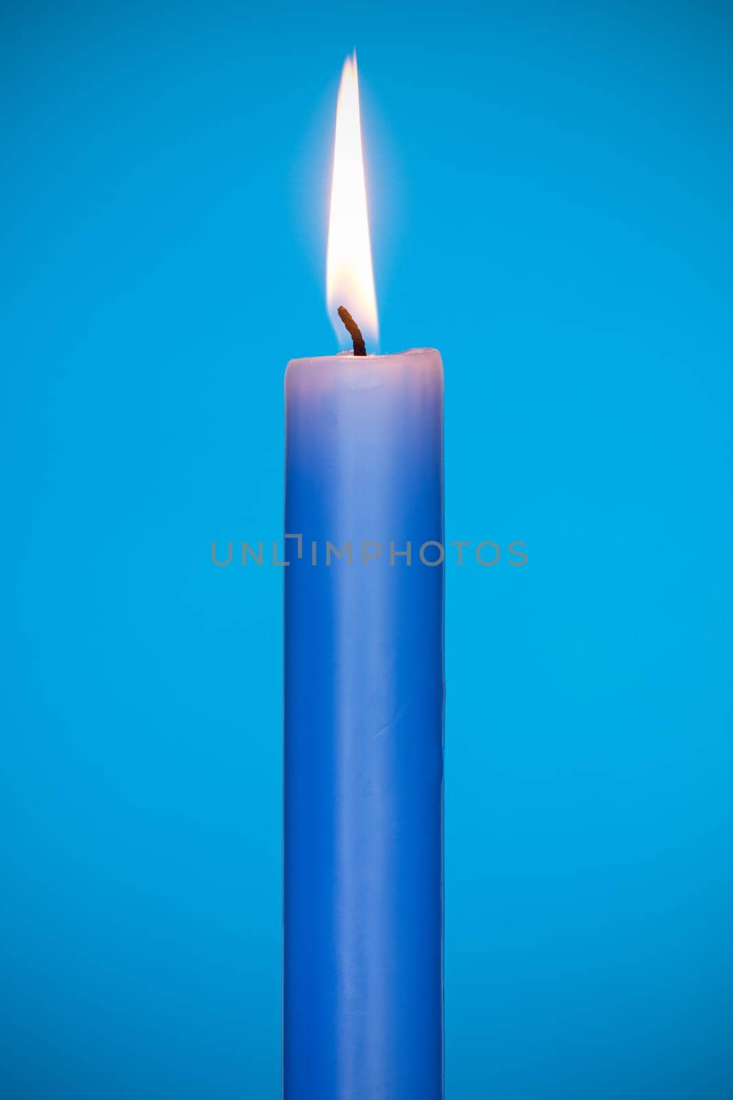 Blue candle burning on the blue background