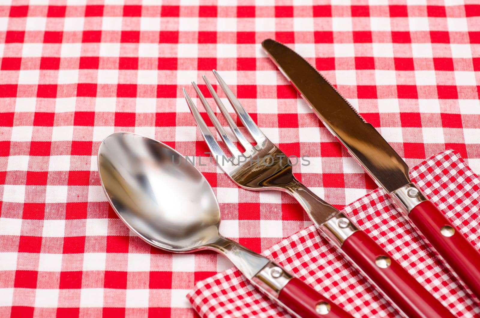 Red cutlery on napkin and tablecloth with checks