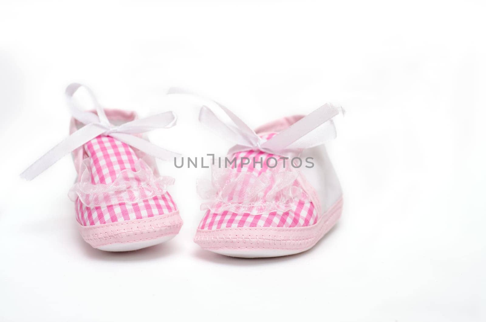 Pair of baby shoes in pink against a white background