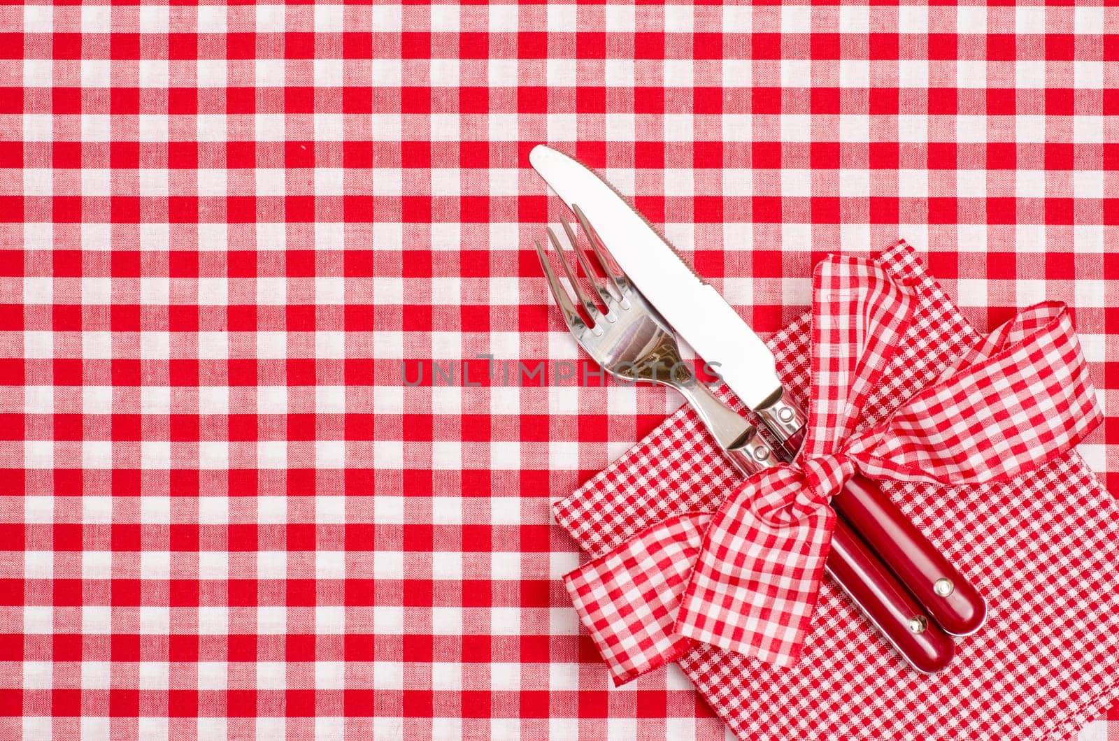 Laid table with cutlery and napkin in red and white with bow