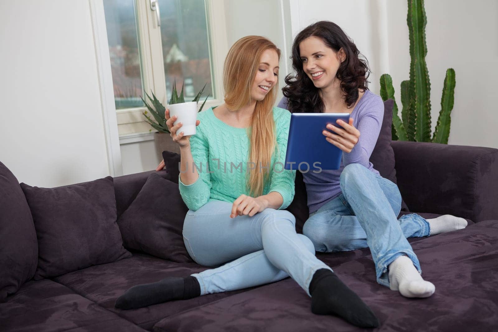 Two Young Happy Women on the Couch with Tablet PC Internet Lifestyle