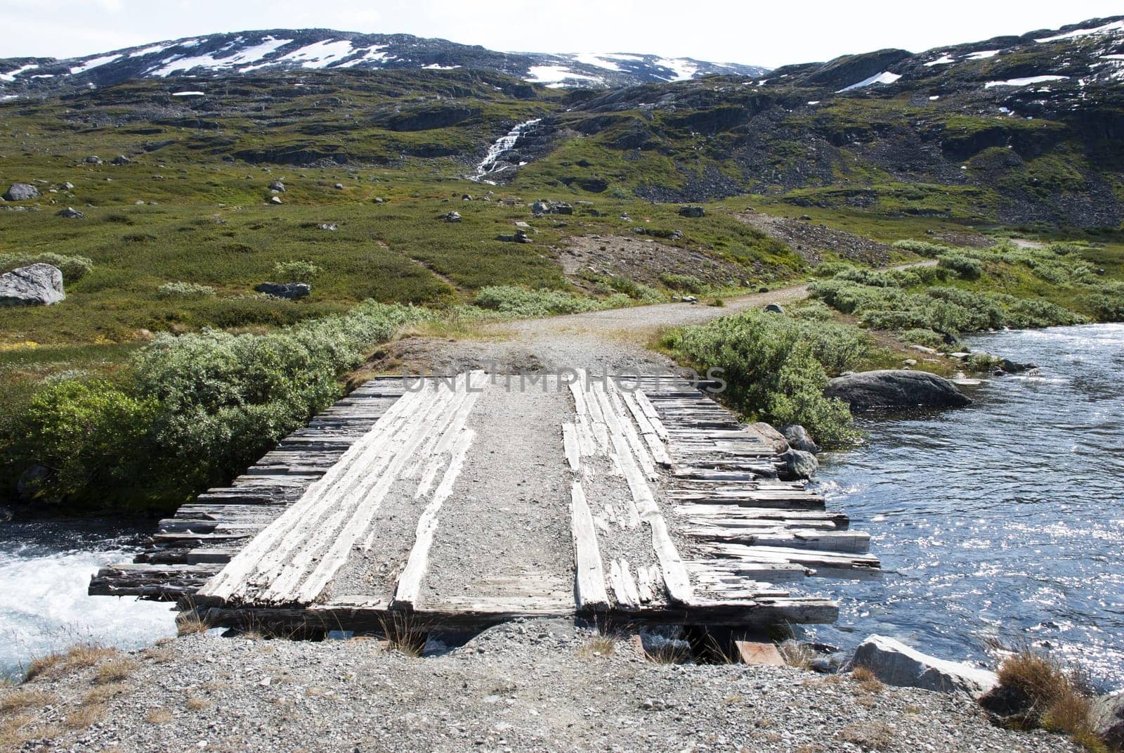 A Plank Bridge in the Mountains Leading over a small River
