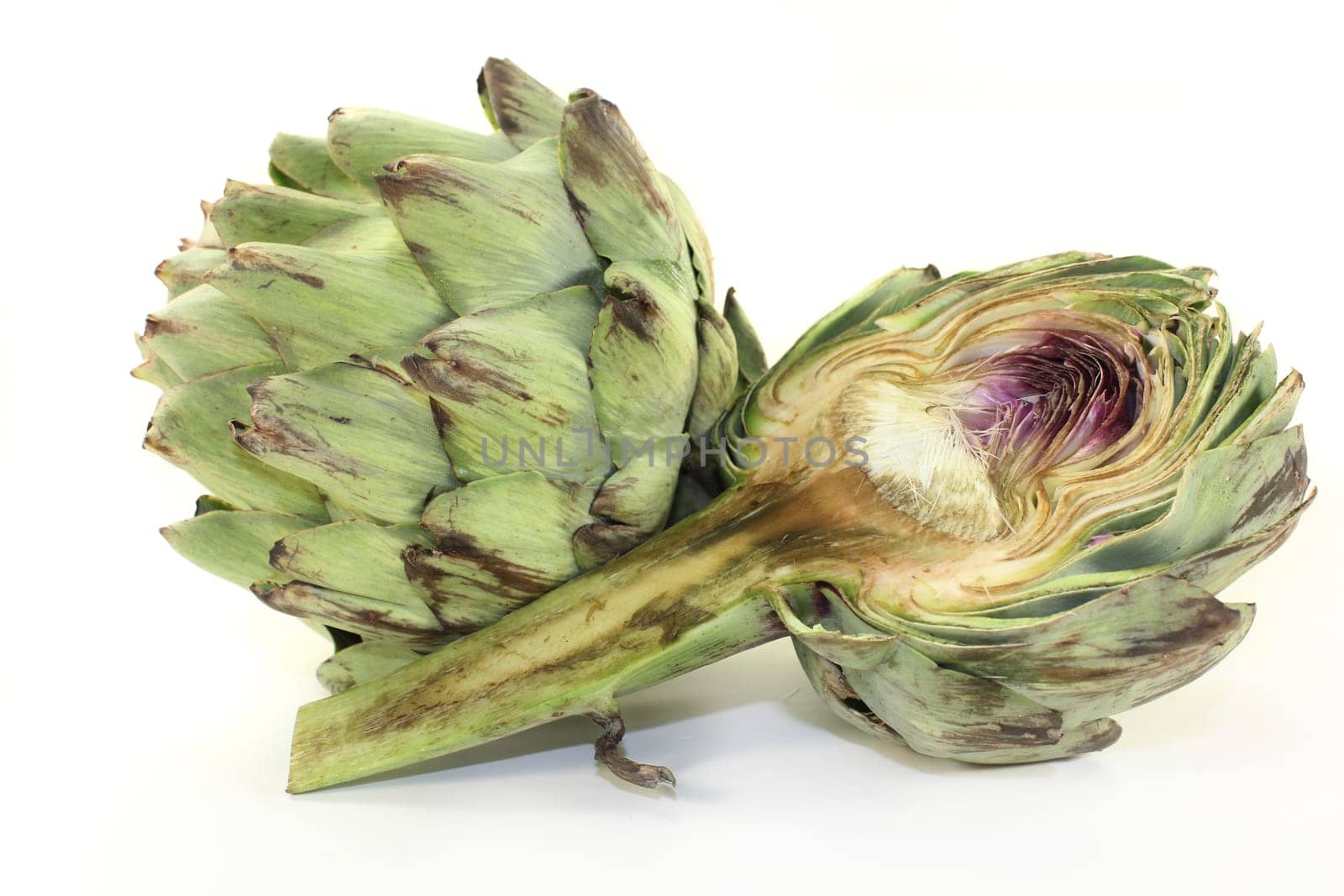 fresh,raw artichokes against a white background
