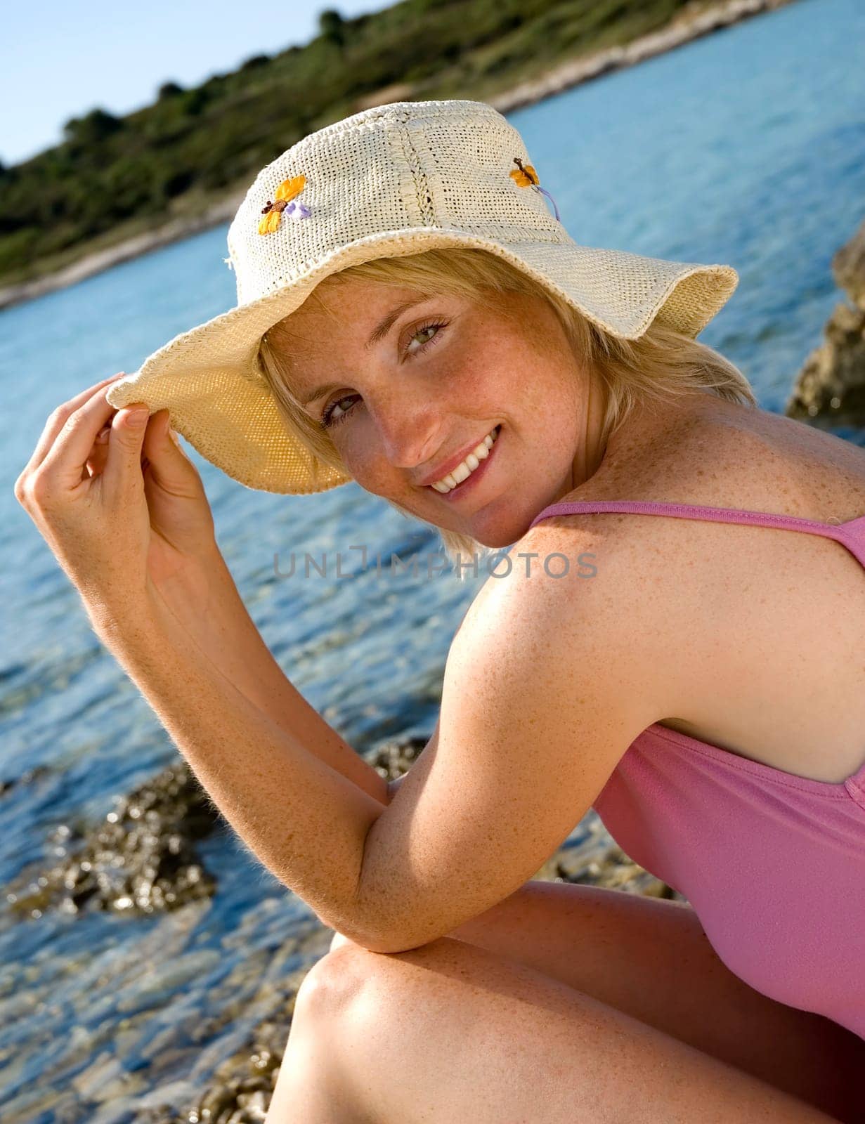 young girl with hat sitting on the beach portrait