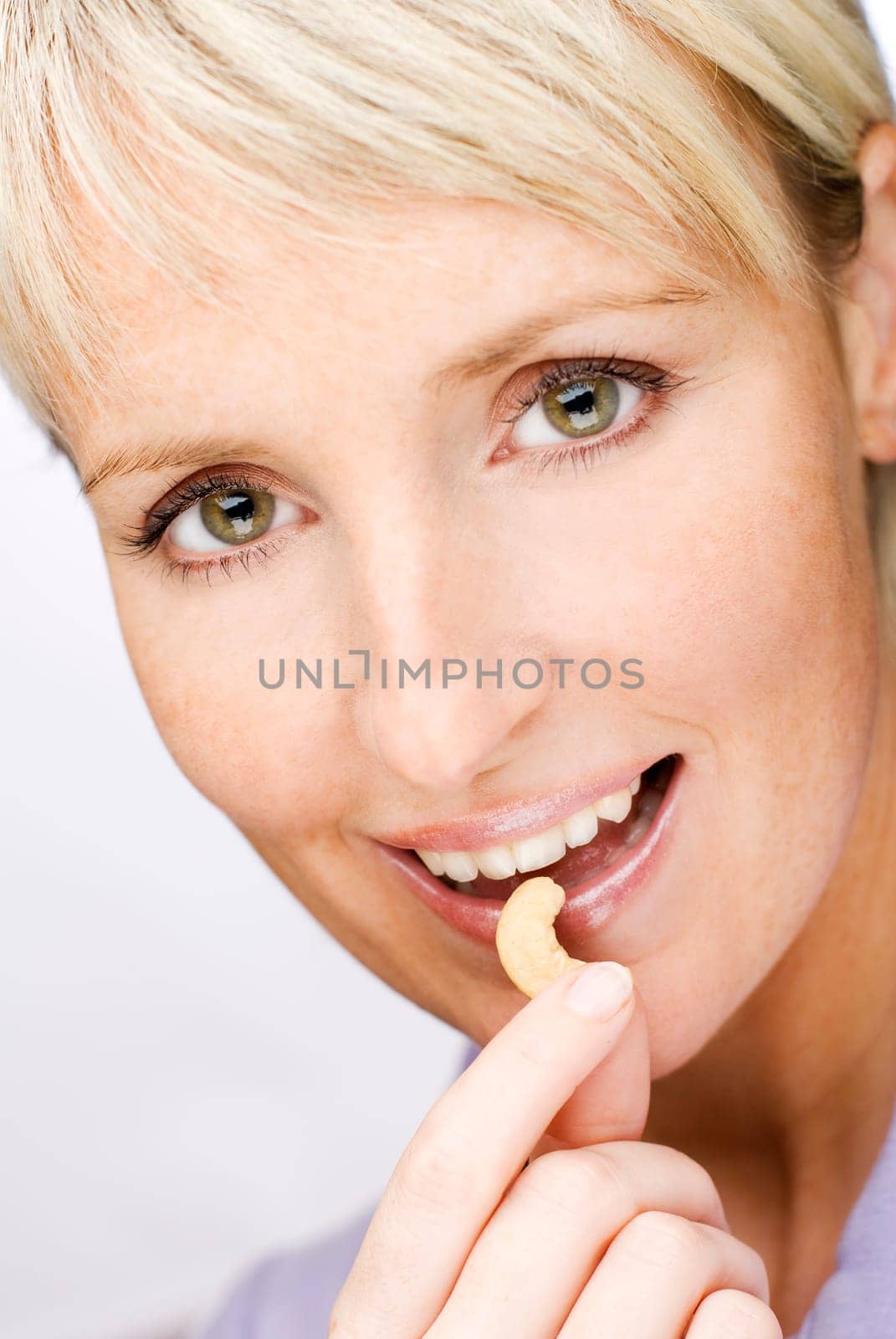young beautiful blond woman eating cashew nuts close up