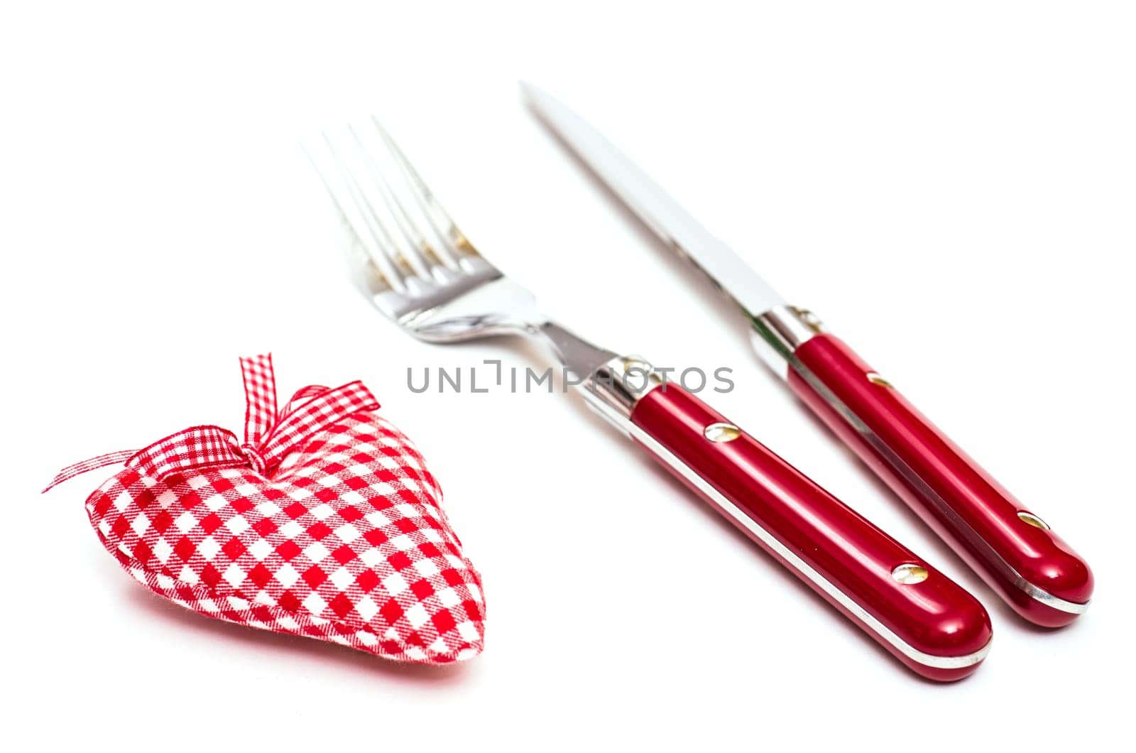Red heart made of fabric and knife and fork on white background