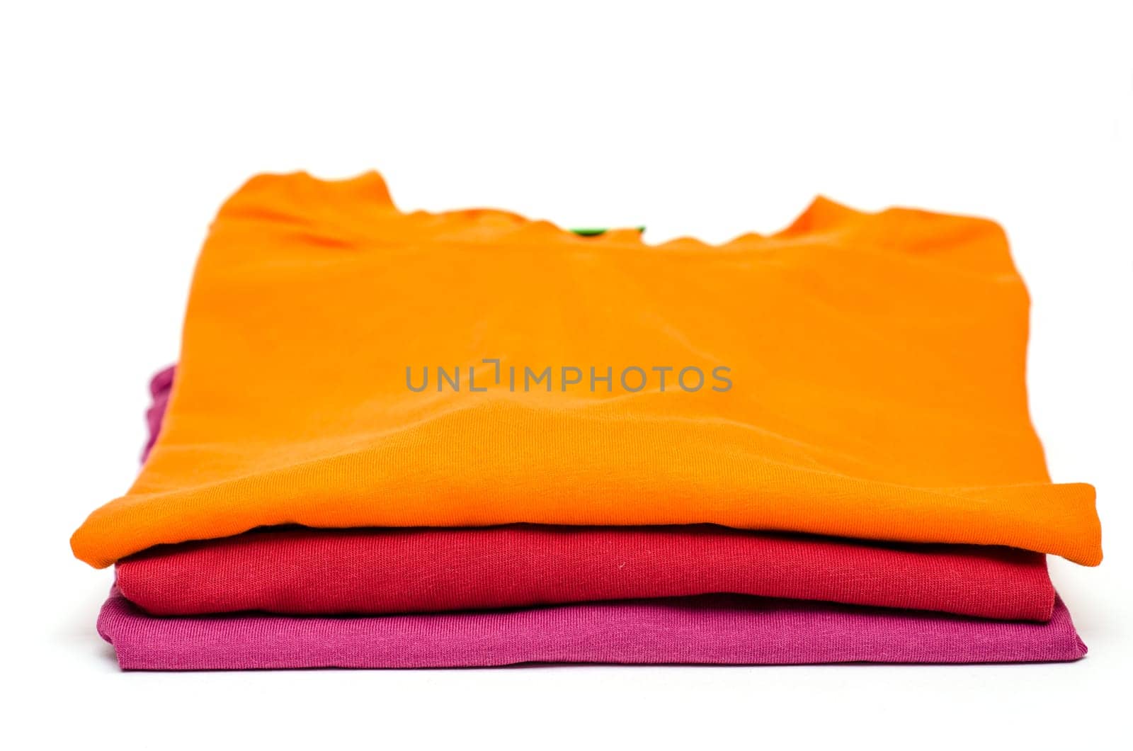 Three T-shirts in orange,red and purple on one pile