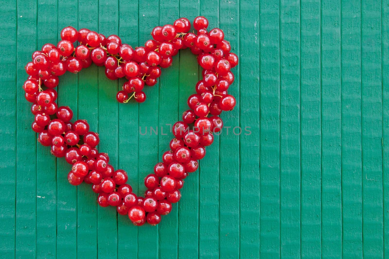 Heart-shaped currants on a green background with free text space