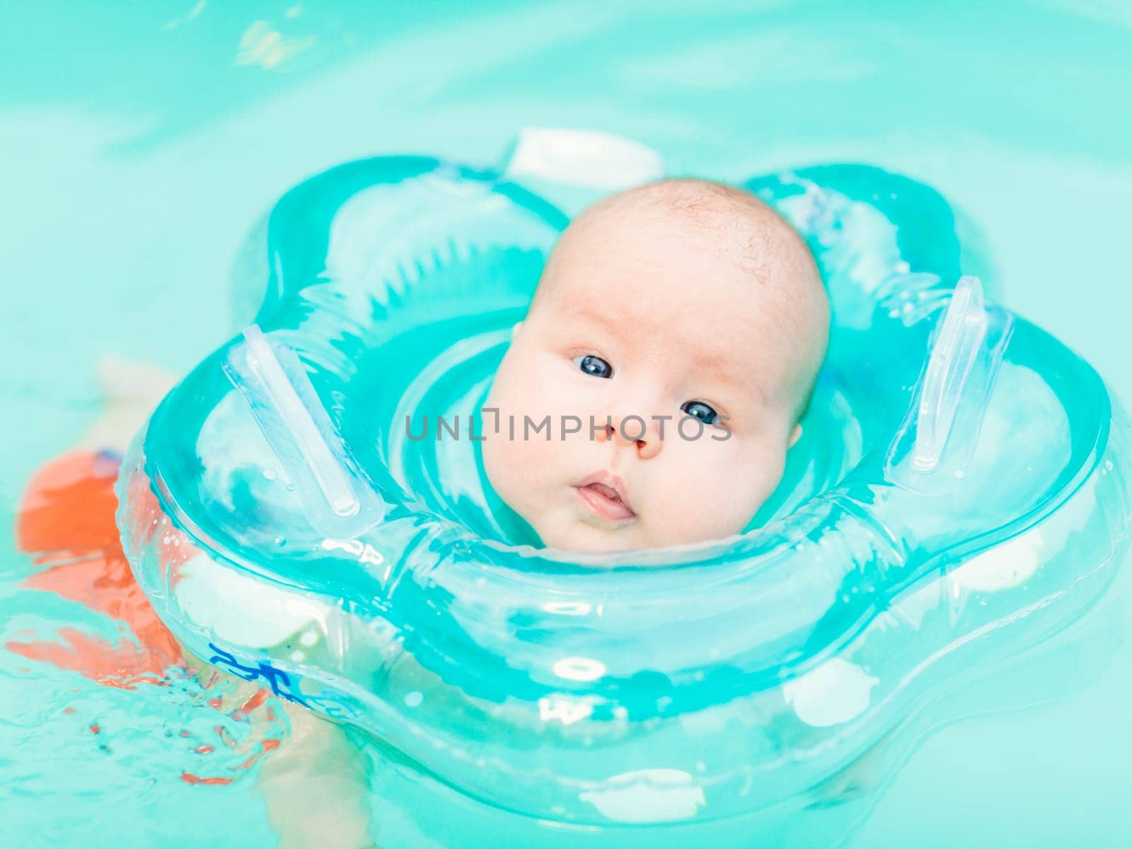 Baby swimming with neck swim ring in pool