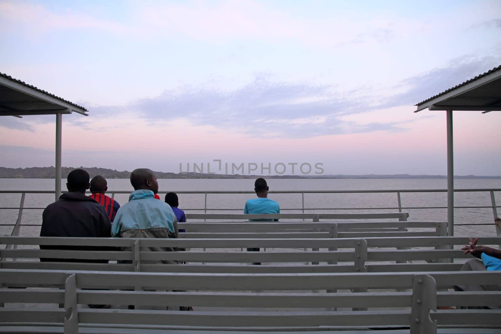 Locals sit and enjoy the sunrise while crossing part of Lake Victoria on the ferry.