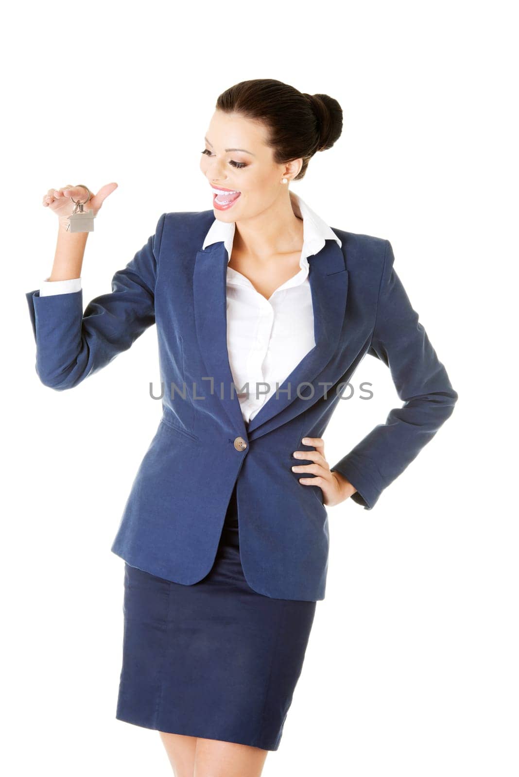 Portrait of a happy attractive caucasian businesswoman, real estate agent, holding a house key against a white background