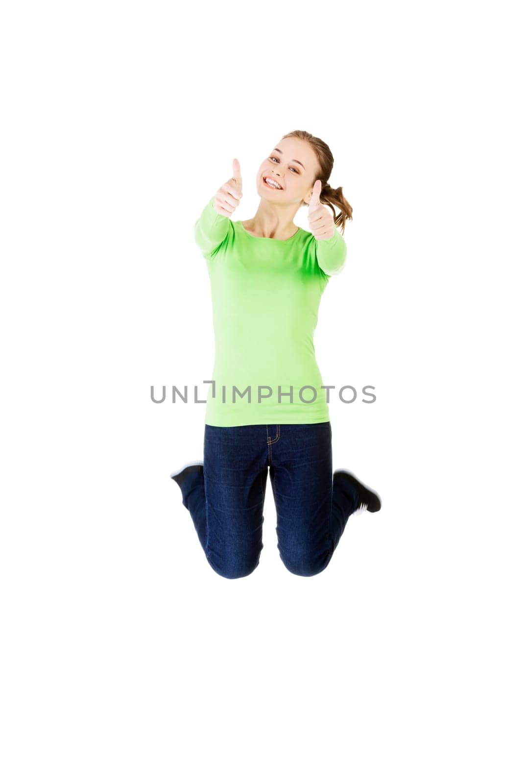 Young happy caucasian woman jumping in the air with thumbs up , isolated on white background