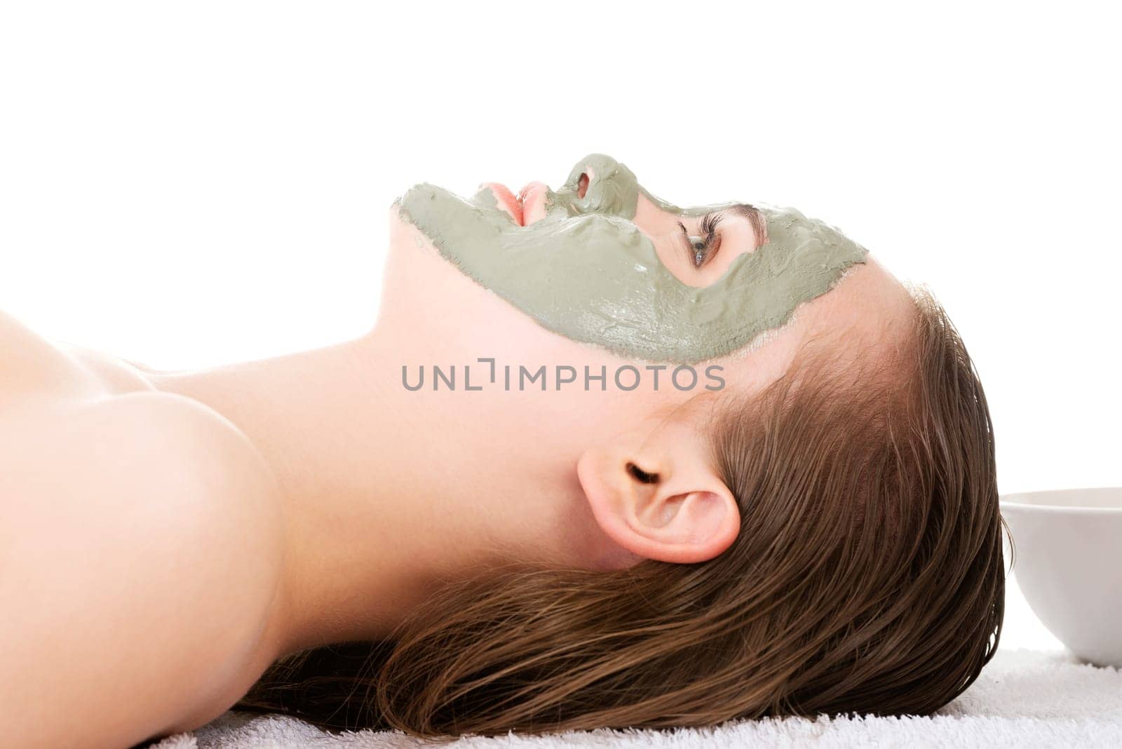 Beauty treatment in spa salon. Woman with facial clay mask. Isolated on white