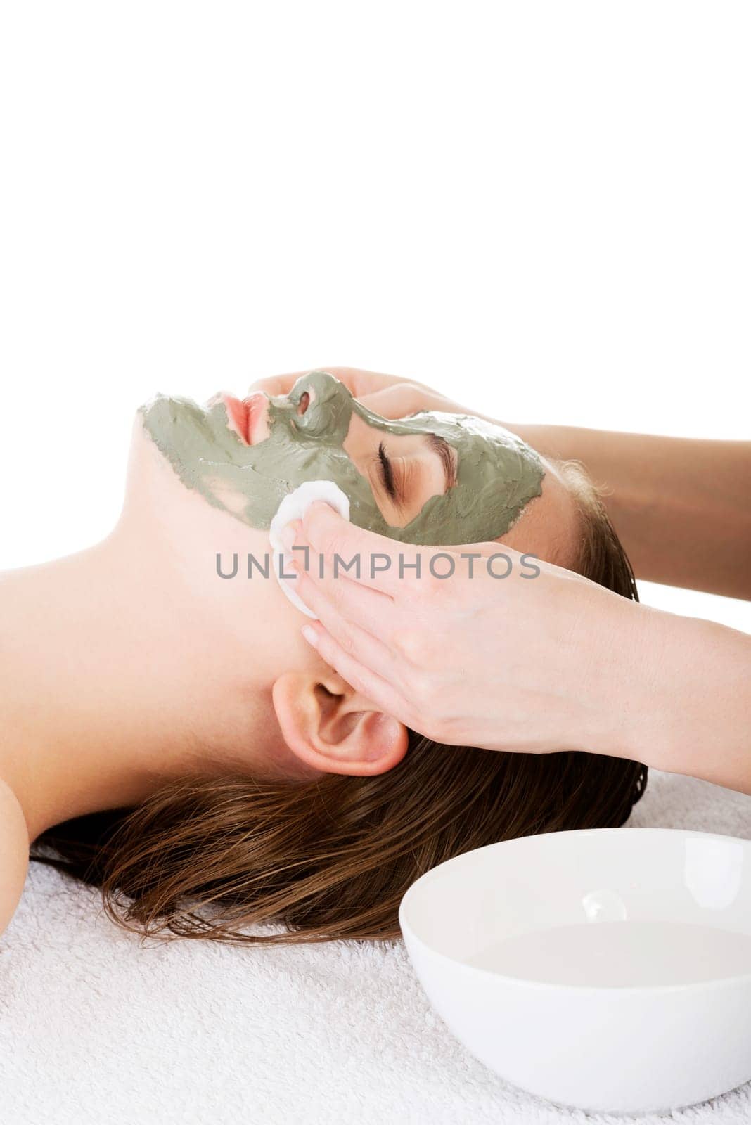 Beauty treatment in spa salon. Woman with facial clay mask. Isolated on white